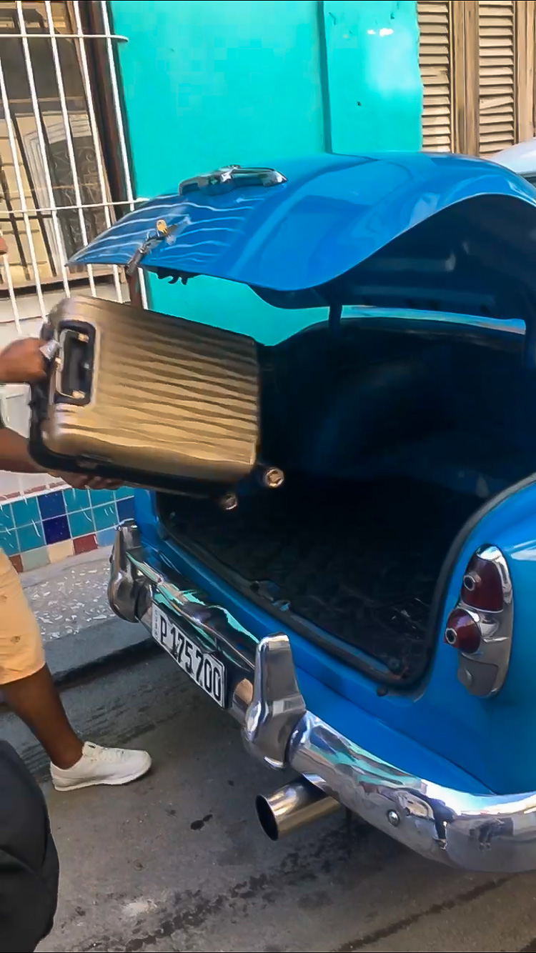 Carry-on bag in old cab car trunk in Havana
